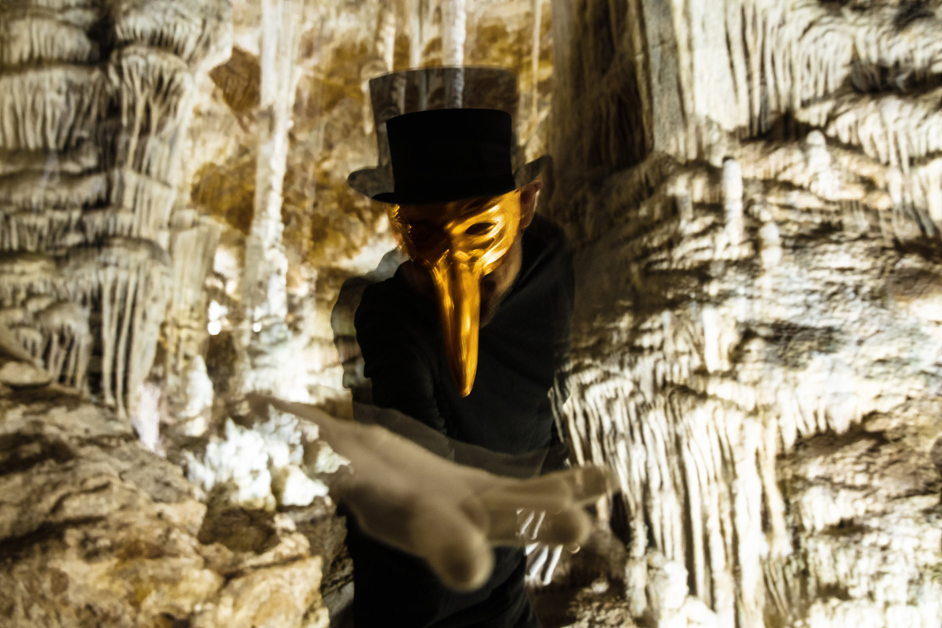 Claptone con su máscara dorada y chistera, actuando en una cueva iluminada